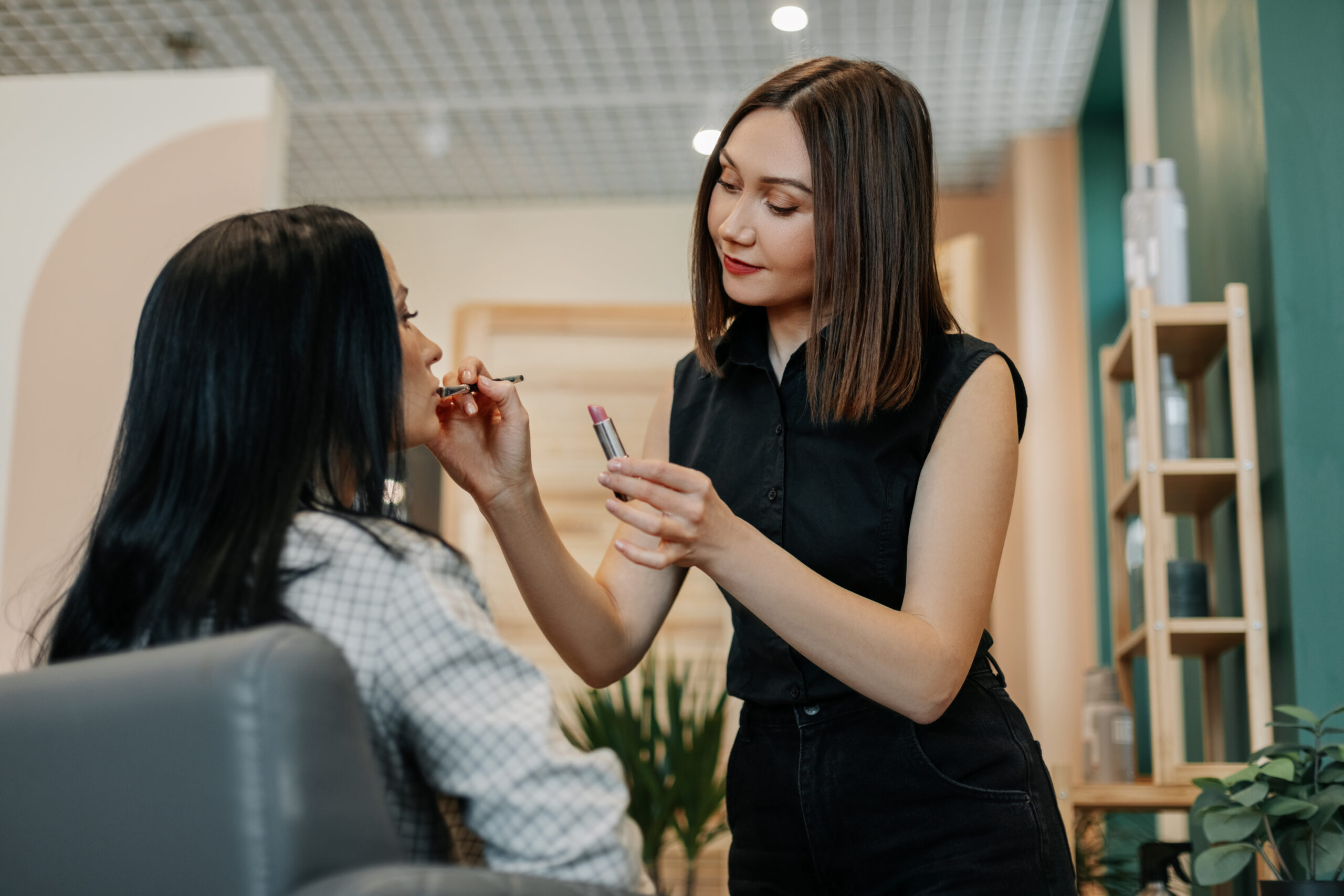 A make up artist makes makeup for a girl in the salon, applies lipstick, completes the image