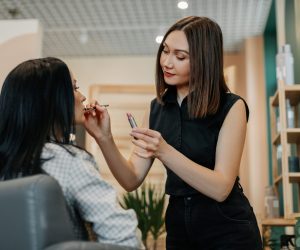 A make up artist makes makeup for a girl in the salon, applies lipstick, completes the image