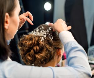 partial view of hairstylist decorating clients hairstyle with beautiful accessory